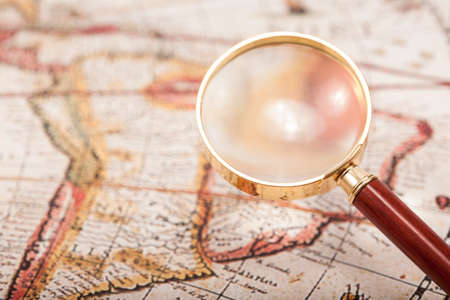 A beautiful antique map with an old magnifying glass with golden details の写真素材