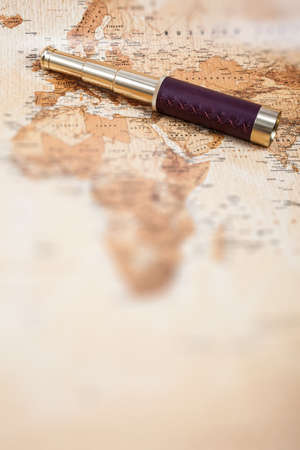 An antique, out of focus, map with a beautiful golden and leather telescope 