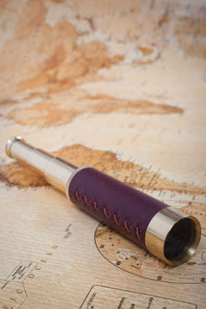 An antique, out of focus, map with a beautiful golden and leather telescope の写真素材