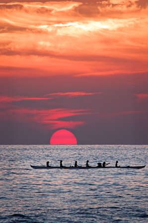 Hawiian women paddling a canoe home at sunset.の写真素材