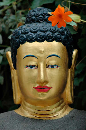 Statue of a Buddha with a red flower.の写真素材