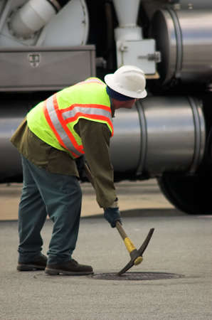 A city workman opening a manhole cover