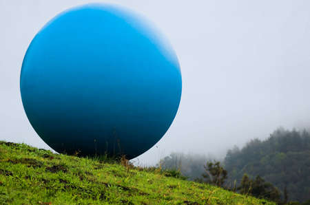 A very large blue ball on a grassy hillsideの写真素材