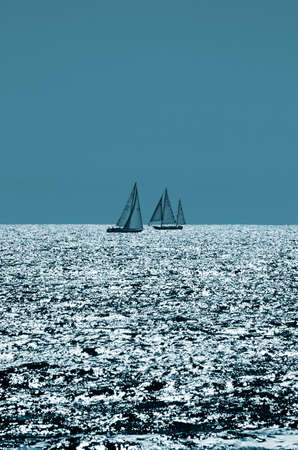 Two sailboats passing on the Pacific Ocean at the end of the dayの写真素材