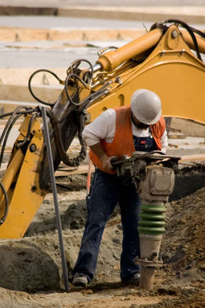 A construction worker using a large soil tamping machine