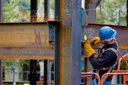 A construction worker welding an iron beam