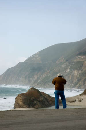 A mature gentleman making a photograph of the mouth of the Little Sur river.の写真素材