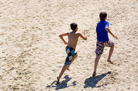 Two friends racing across a sandy beach in Californiaの写真素材