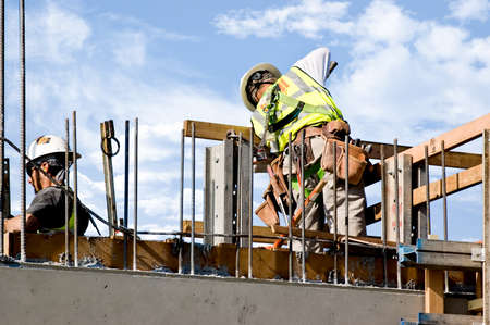 Workmen releasing a concrete form on a high wall.