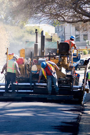 Men on an asphalt paver repairing a road.の写真素材