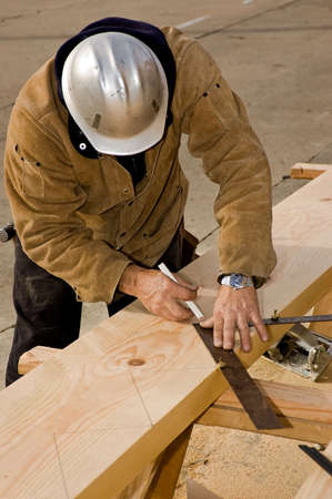A carpenter laying out the cuts for a stair stringer.