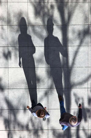Two people walking down the street in the late afternoon.の写真素材