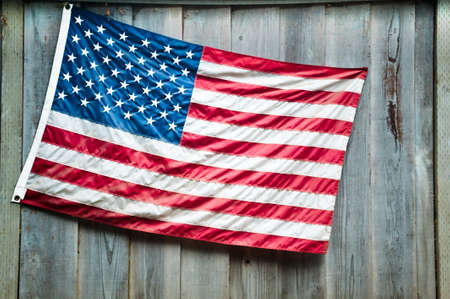 An American flag hung from a wooden fenceの写真素材