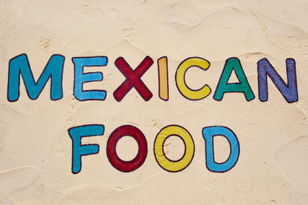 Brightly colored restaurant sign painted on a stucco wallの写真素材