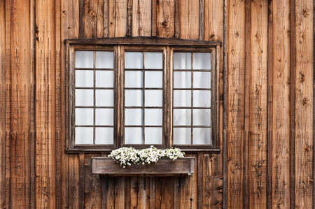 Rustic unpainted cabin window with a flower boxの写真素材