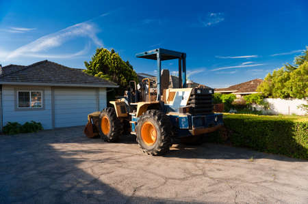 A large tractor parked in front of a house.の写真素材