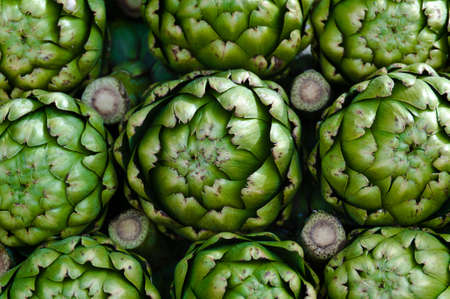 Piled artichokes in a vendor's stall at the farmers marketの写真素材