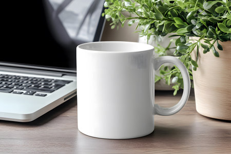 White mug mockup on wooden table with laptop and green plant.の写真素材