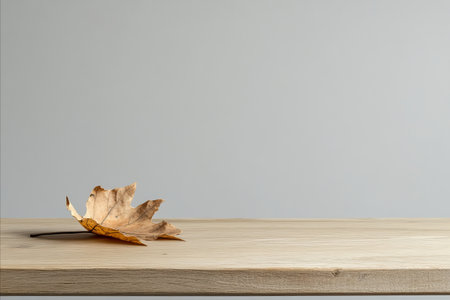 Wooden table with autumn leaves on grey background. For product displayの写真素材