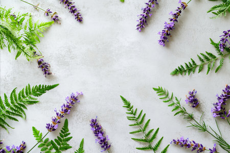 A beautiful arrangement of fresh lavender flowers and green fern leaves creating a natural frame on a clean white surface, perfect for a serene and organic feel.の写真素材