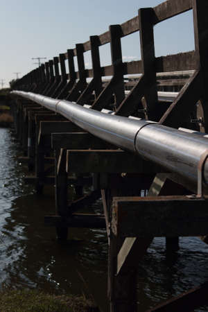 A vertical closeup shot of a steel pipe on a wooden bridgeの写真素材