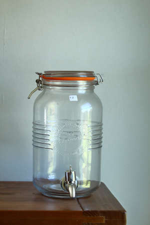 Glass jar on a wooden shelf against a white wallの写真素材