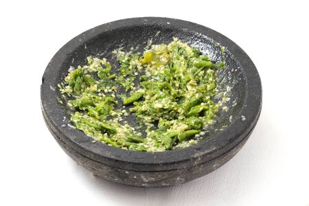 Sambal ijo or traditional green chili sauce from Indonesia, freshly made using stone mortar and pestle, isolated on white backgroundの写真素材