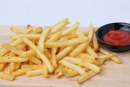 Tasty french fries or kentang goreng on cutting board  on wooden table background isolated on white