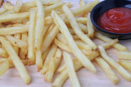 Tasty french fries or kentang goreng on cutting board  on wooden table background isolated on white