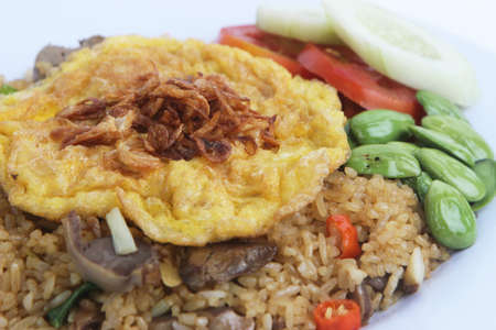 Nasi goreng fried rice with pete and egg garnished with fresh cucumber slices and prawn crackers on a plate on a cloth. Asian food.の写真素材