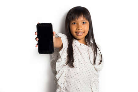 Happy asian little girl using smart phone on white backgroundの写真素材