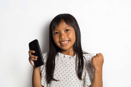 Happy asian little girl using smart phone on white background
