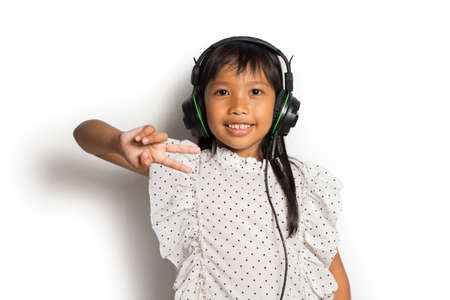 Asian Little girl with headphones listening music enjoy and dance on white backgroundの写真素材