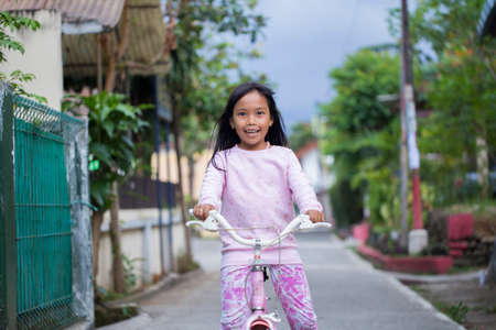 happy asian little girl riding on bicycleの写真素材
