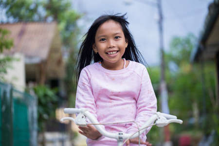 happy asian little girl riding on bicycleの写真素材