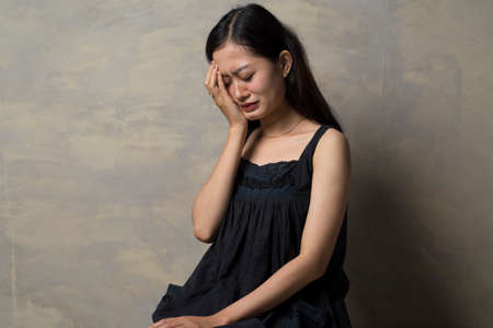 Sad young Asian woman cry with palm to faceの写真素材