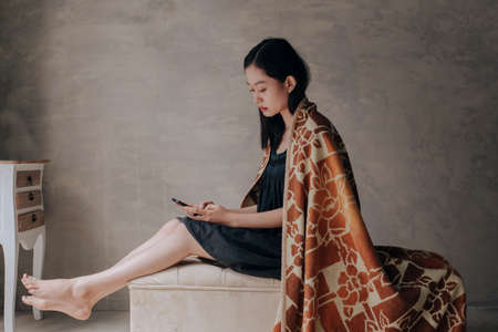 Sad young asian woman holding her smartphone