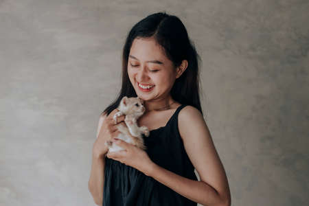 Young Asian woman holding and playing with her cute kitten cat with lovely moment