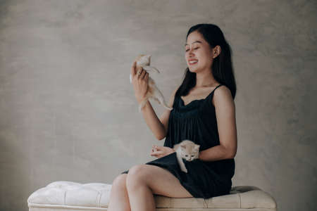 Young Asian woman holding and playing with her cute kitten cat with lovely momentの写真素材