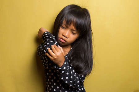 Asian little girl having pain in injured elbow.
