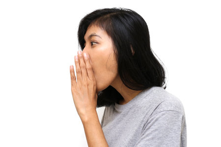 Young asian woman isolated white background hand on mouth telling secret rumor, whispering malicious...
