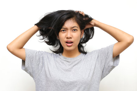 Closeup portrait of asian young woman scratching head with handの写真素材