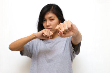 Portrait of asian young woman looking at camera ready to fight, fist close upの写真素材