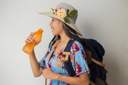 Asian woman tourist with backpack drinking water isolated on white backgroundの写真素材