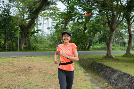 A portrait of a young asian woman doing excercise outdoor in a park, joggingの写真素材