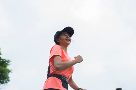 A portrait of a young asian woman doing excercise outdoor in a park, jogging