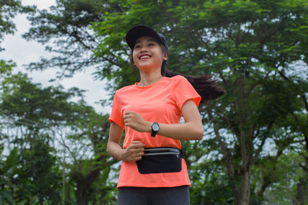 A portrait of a young asian woman doing excercise outdoor in a park, jogging