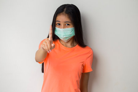 Sporty asian girl wearing medical face mask to protection corona virus, covid-19  posing on the gray backgroundの写真素材
