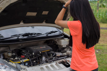 Asian woman checking broken down car on streetの写真素材