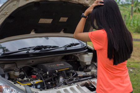 Asian woman checking broken down car on streetの写真素材